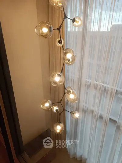 Elegant modern lighting fixture with glass globes near a window with sheer curtains, adding sophistication to the space.