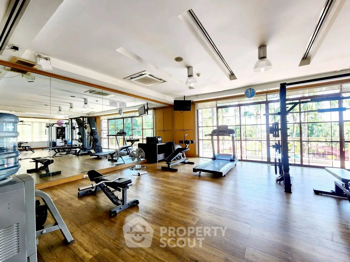 Spacious gym with modern equipment and large windows offering scenic views.