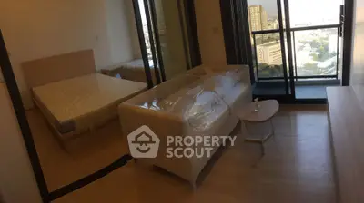 Modern apartment with bedroom and living area, featuring large windows and a balcony with city view.
