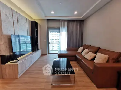 Spacious modern living room with large TV and leather sofa, featuring a balcony view.