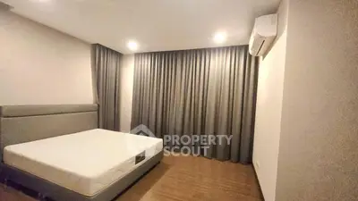 Spacious bedroom with modern design and air conditioning, featuring elegant curtains and wooden flooring.