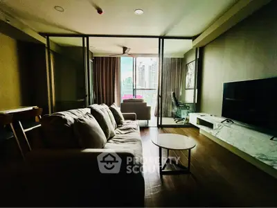 Modern living room with large windows and city view, featuring a comfortable sofa and sleek TV setup.