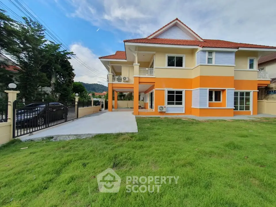 Spacious two-story house with vibrant orange accents and lush green lawn, perfect for family living.