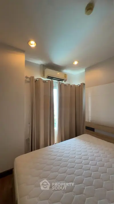 Cozy bedroom with natural light, featuring a comfortable bed and air conditioning, perfect for relaxation.