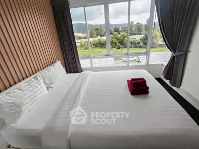 Spacious bedroom with large windows offering scenic views and modern decor.