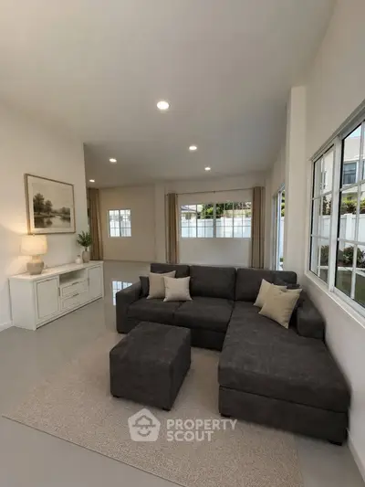 Spacious living room with modern sectional sofa and large windows offering natural light.