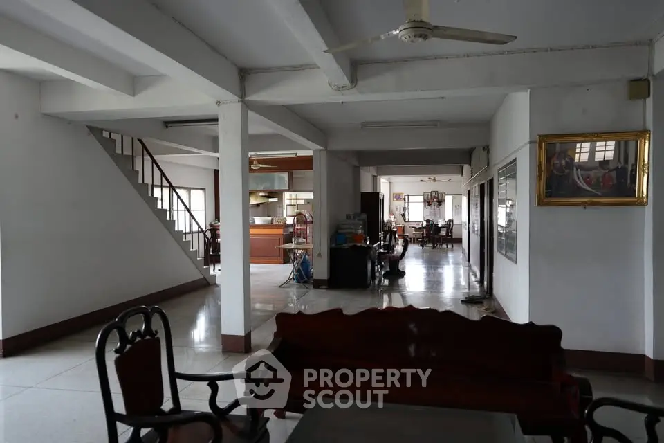 Spacious open-plan living area with elegant wooden furniture and staircase, ideal for family gatherings.