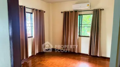 Spacious empty room with hardwood floors and large windows, perfect for customization.