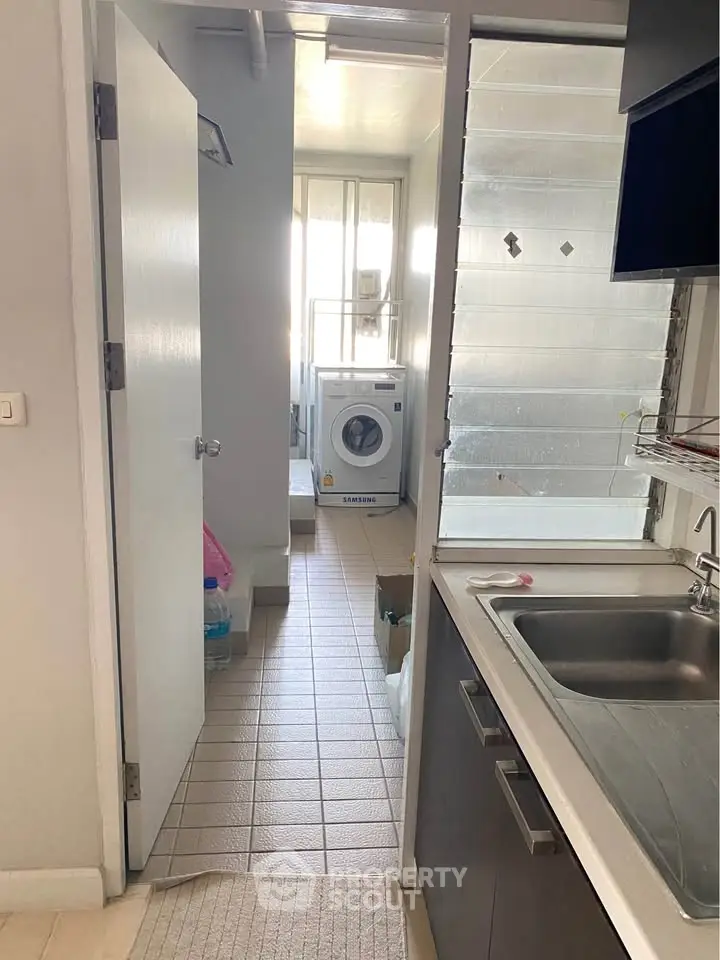 Compact kitchen with modern sink and washing machine in bright utility area.
