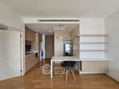 Modern kitchen with open layout and integrated dining area, featuring sleek cabinetry and wooden flooring.