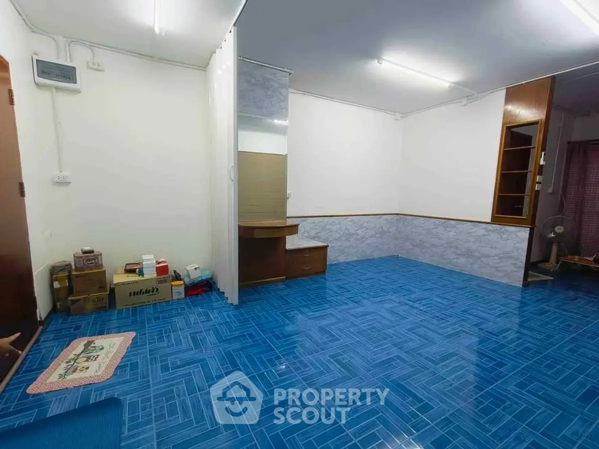 Spacious room with vibrant blue flooring and ample storage space, ideal for versatile living arrangements.