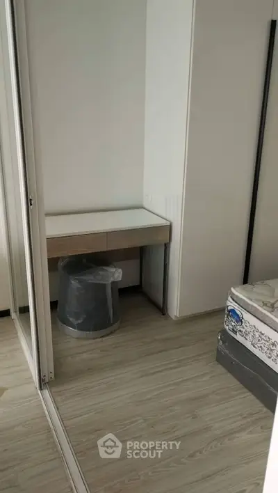 Compact bedroom with mirrored closet and wooden flooring