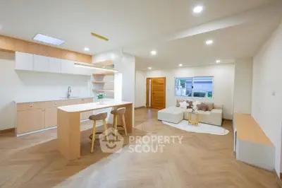 Modern open-plan kitchen and living room with stylish wooden flooring and contemporary furniture.