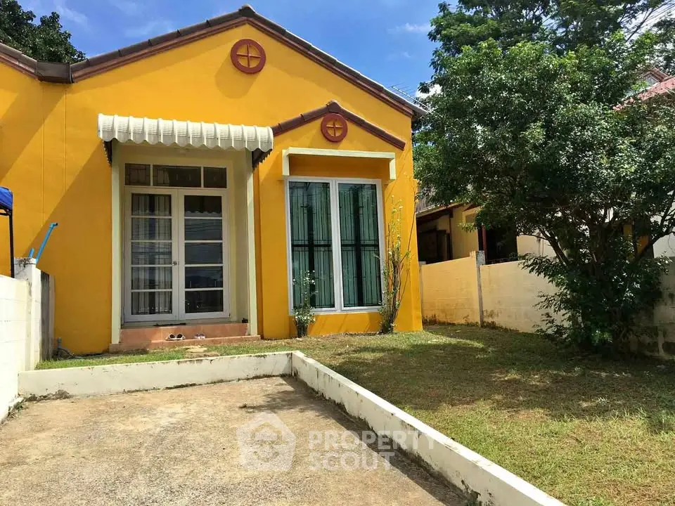 Charming yellow house with lush garden and spacious driveway, perfect for family living.