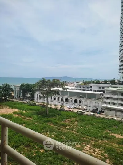 Stunning coastal view from a high-rise balcony overlooking lush greenery and ocean horizon.