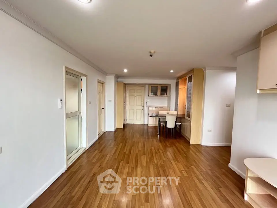 Spacious open-plan living area with wooden flooring and modern dining setup.