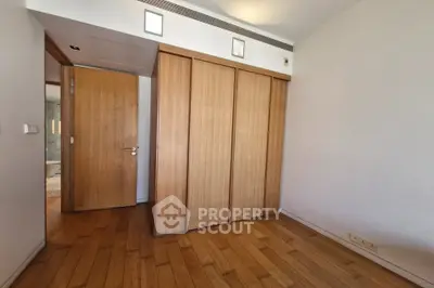 Spacious bedroom with wooden flooring and built-in closet in modern apartment.