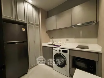 Modern kitchen with sleek cabinetry, washing machine, and built-in appliances in a compact layout.