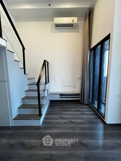 Modern duplex interior with sleek staircase and large windows, perfect for urban living.