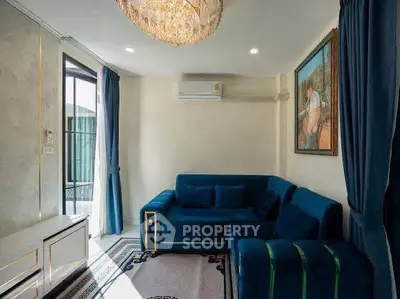 Elegant living room with plush blue sofas, modern chandelier, and balcony access, perfect for stylish urban living.