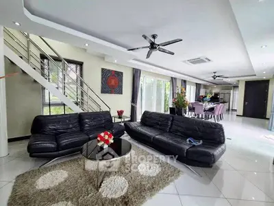 Spacious modern living room with sleek black leather sofas and open dining area, perfect for entertaining.