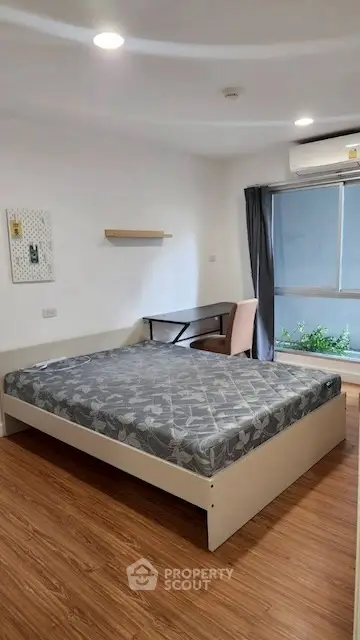 Modern bedroom with wooden flooring and large window for natural light.
