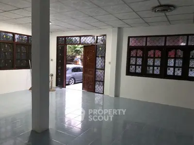 Spacious open-plan area with large windows and tiled flooring, ideal for versatile use.