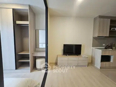 Modern studio apartment with open wardrobe, TV unit, and compact kitchen.