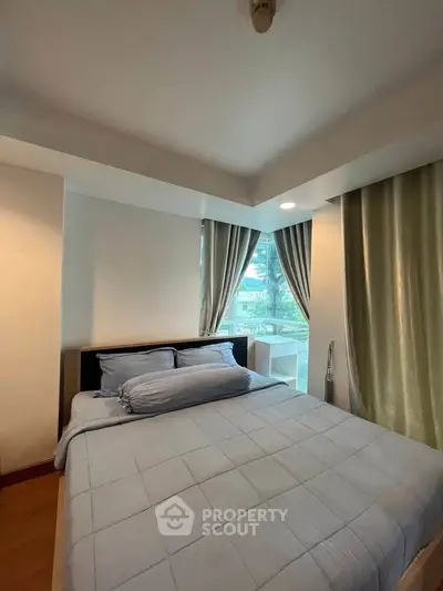 Cozy bedroom with large window and soft lighting in modern apartment.