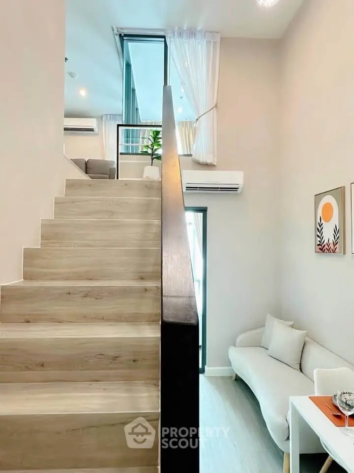 Modern duplex interior with stylish staircase and cozy living area, featuring elegant decor and natural light.