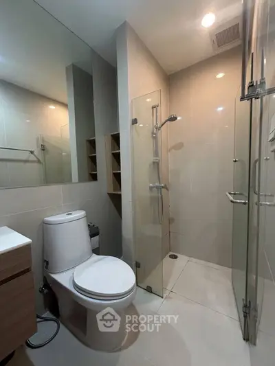 Modern bathroom with glass shower and sleek fixtures in contemporary apartment.