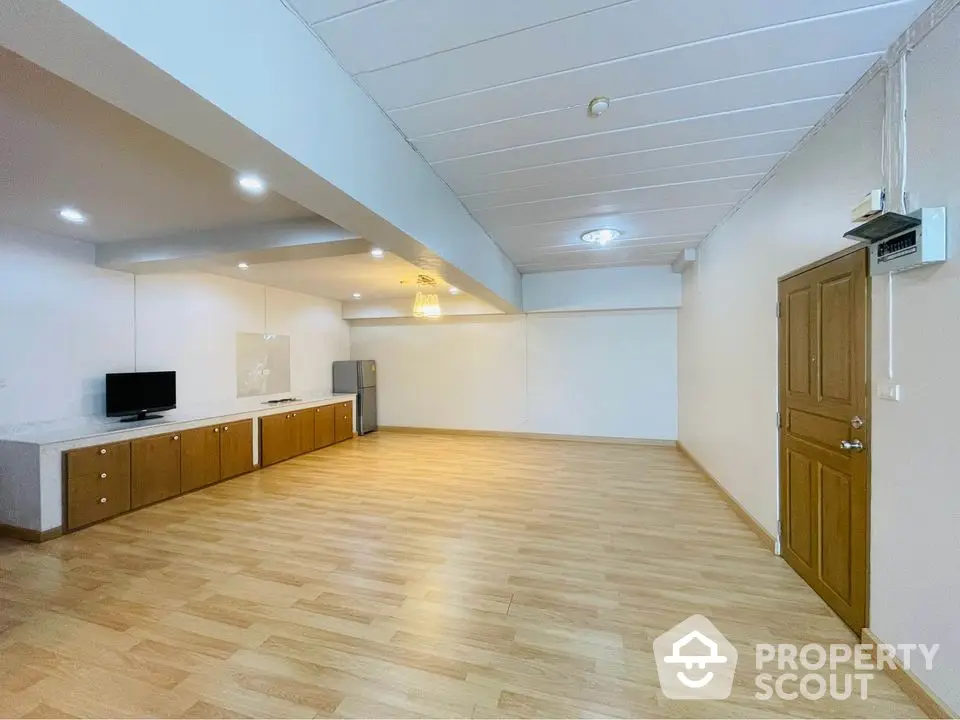 Spacious open-plan living area with wooden flooring and modern lighting, ideal for versatile interior design.