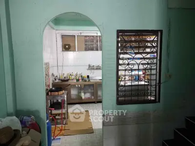 Cozy kitchen with open layout and vintage charm, featuring a window with decorative grill and tiled flooring.