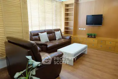 Modern living room with leather sofas, wooden blinds, and mounted TV for a cozy ambiance.