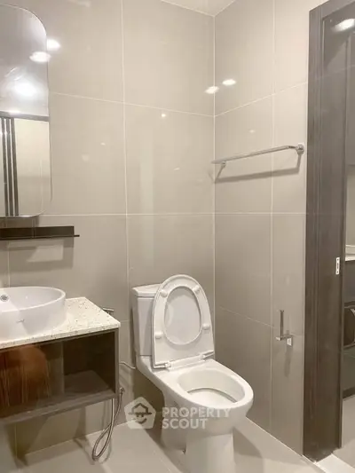 Modern bathroom with sleek fixtures and neutral tiles, featuring a stylish vanity and toilet.