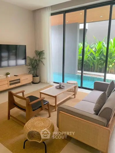 Modern living room with pool view, stylish furniture, and large glass doors.