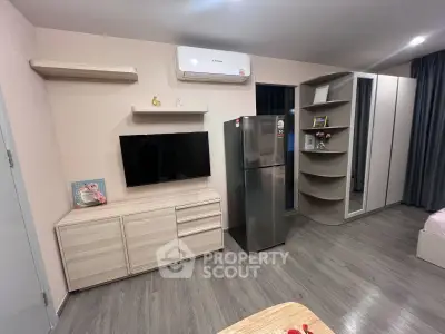 Modern living room with sleek furniture and stainless steel fridge, featuring stylish storage solutions.