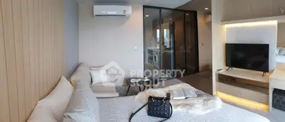 Modern bedroom with stylish decor, featuring a cozy bed, sleek TV setup, and a glass-enclosed laundry area.