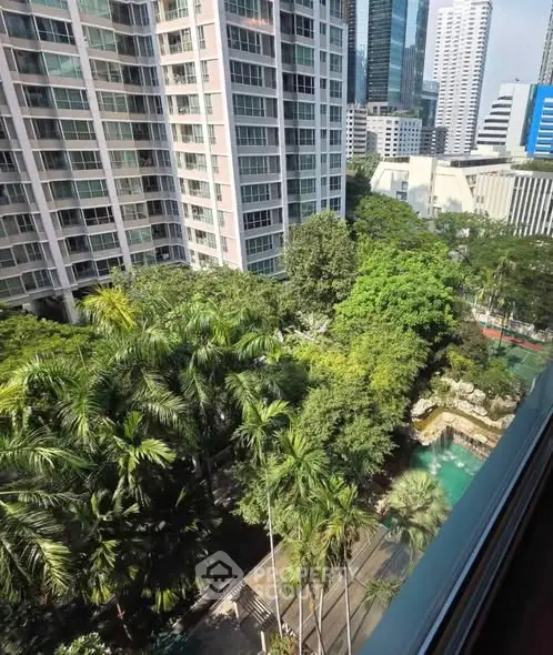 Stunning cityscape view from high-rise apartment with lush greenery and pool area.