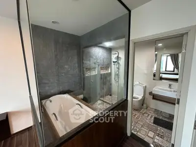 Modern bathroom with glass partition and stylish bathtub in contemporary apartment.
