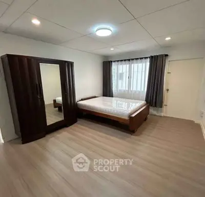 Spacious bedroom with wooden furniture and large window for natural light