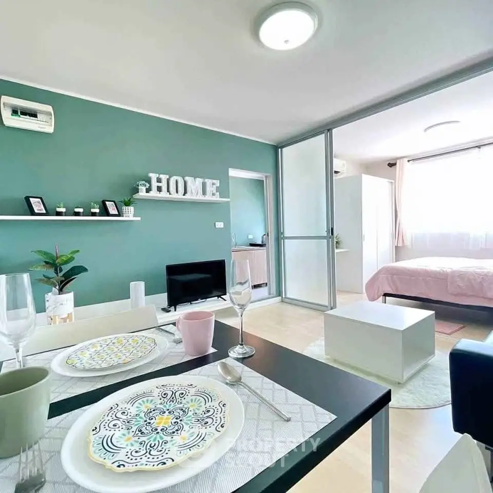 Modern open-plan living room and bedroom with stylish decor and green accent wall.