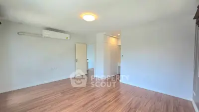 Spacious empty room with wooden flooring and air conditioning, ideal for customization.
