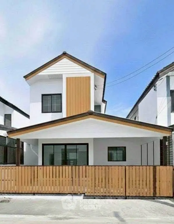 Modern two-story house with wooden accents and a fenced front yard.