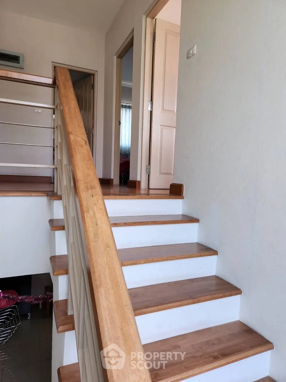 Modern staircase with wooden railing leading to upper floor in a stylish home