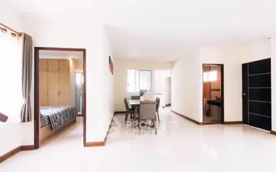 Spacious open-plan living area with dining space and bedroom view, featuring modern decor and ample natural light.