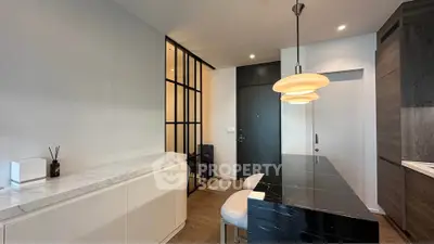 Modern kitchen with sleek black countertop and stylish pendant lights in a contemporary apartment.