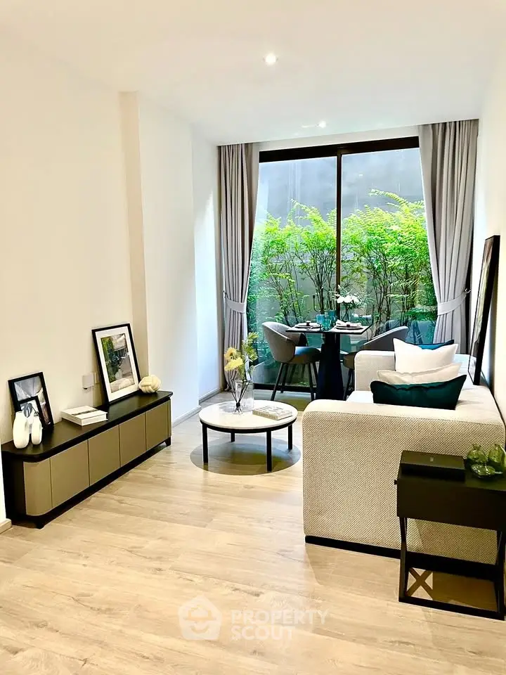 Modern living room with elegant decor and large window opening to a lush green view, perfect for relaxation.