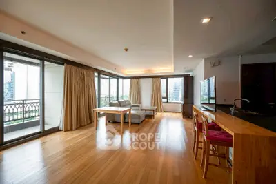 Spacious modern living room with hardwood floors and large windows offering city views.