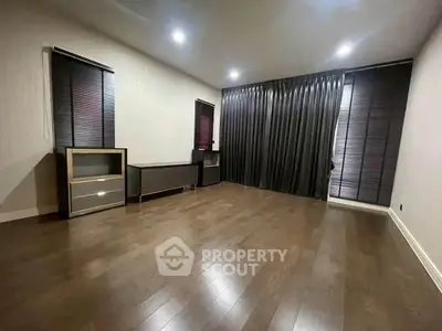 Spacious empty room with wooden flooring and modern window treatments, ideal for customization.